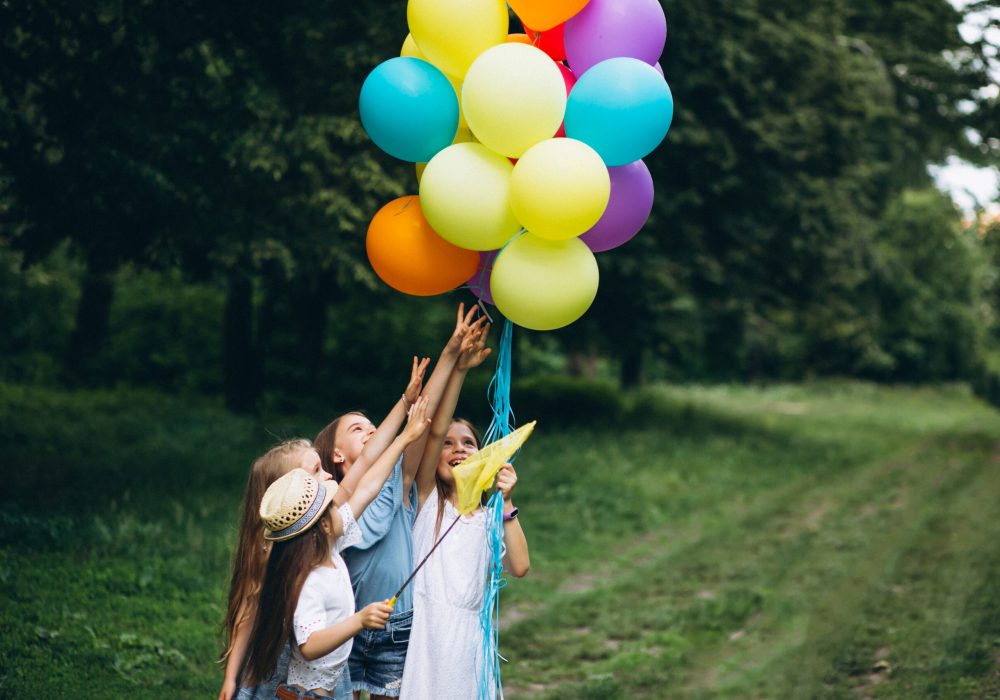 Little girls friends with balloons in forest